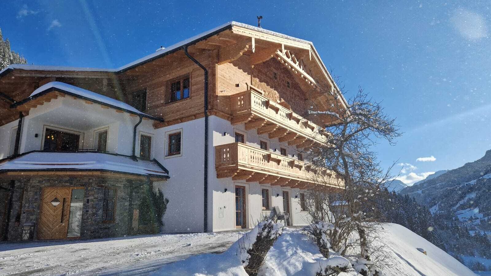 Außenansicht des Bauernhofs im Winter, mit traditioneller Architektur, Holzbalkonen und schneebedeckter Landschaft.