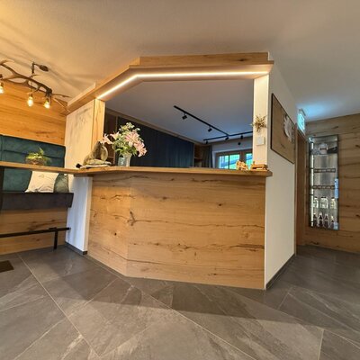 Der Empfangsbereich des Bauernhofs mit Holztheke, Sitzbank und Auslagen.