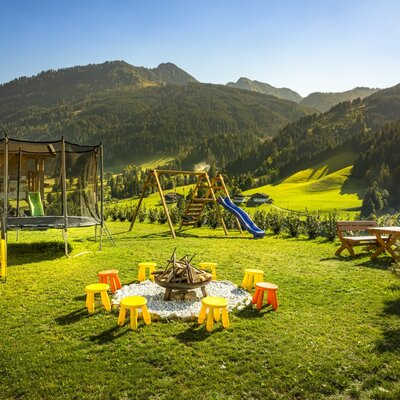 Der weitläufige Garten des Bauernhofs mit einem Spielplatz, einer gemütlichen Feuerstelle und herrlicher Aussicht auf die umliegenden Berge.
