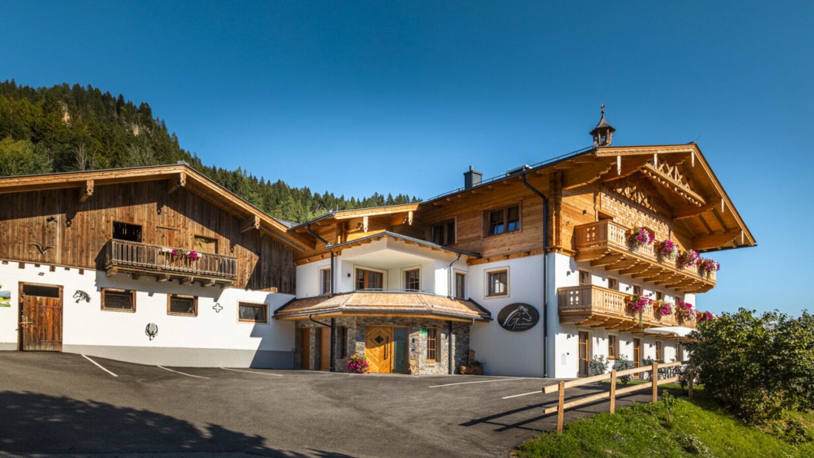 Der einladende Bauernhof mit traditionellen Holzbalkonen vor einer malerischen Bergkulisse.