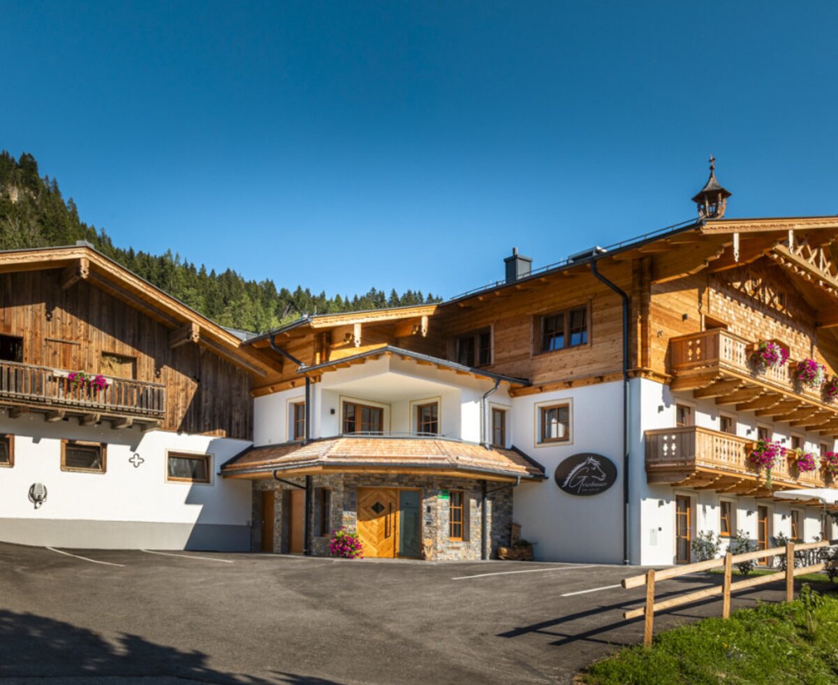 Der einladende Bauernhof mit traditionellen Holzbalkonen vor einer malerischen Bergkulisse.
