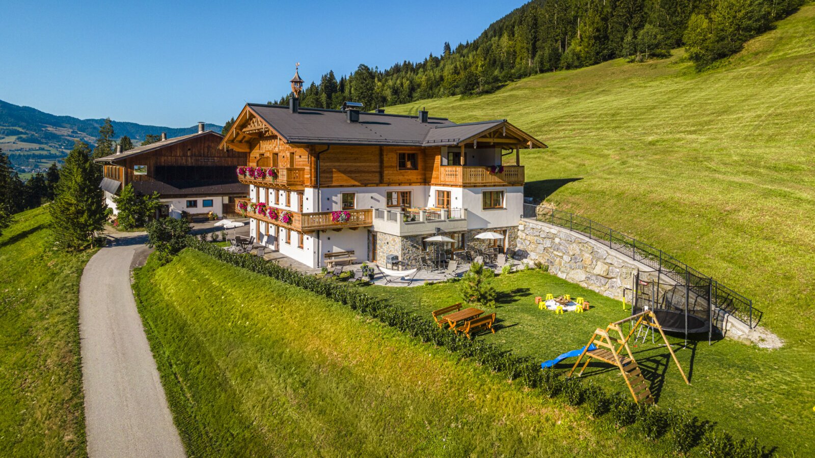 Der einladende Bauernhof besticht durch einen weitläufigen Garten mit Kinderspielplatz und einer sonnigen Terrasse inmitten grüner Natur.