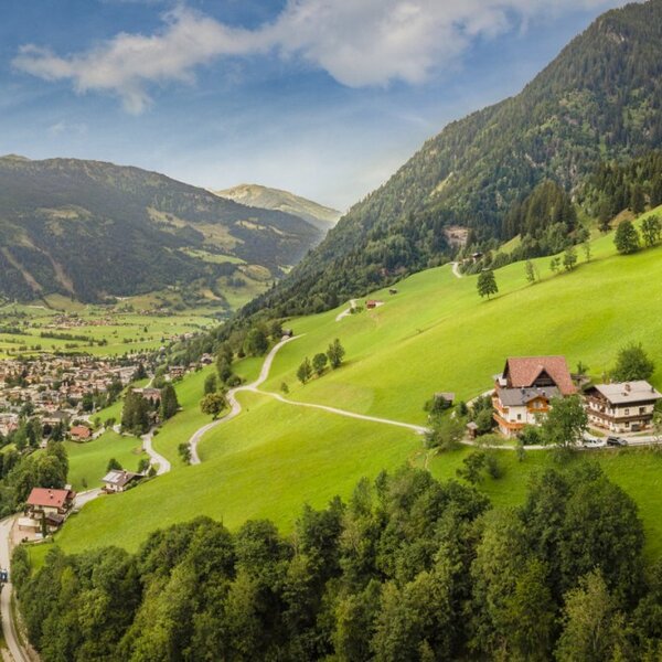 Malerischer Blick auf den Bauernhof, eingebettet in saftig grüne Almwiesen mit einem weiten Panorama über das umliegende Tal.