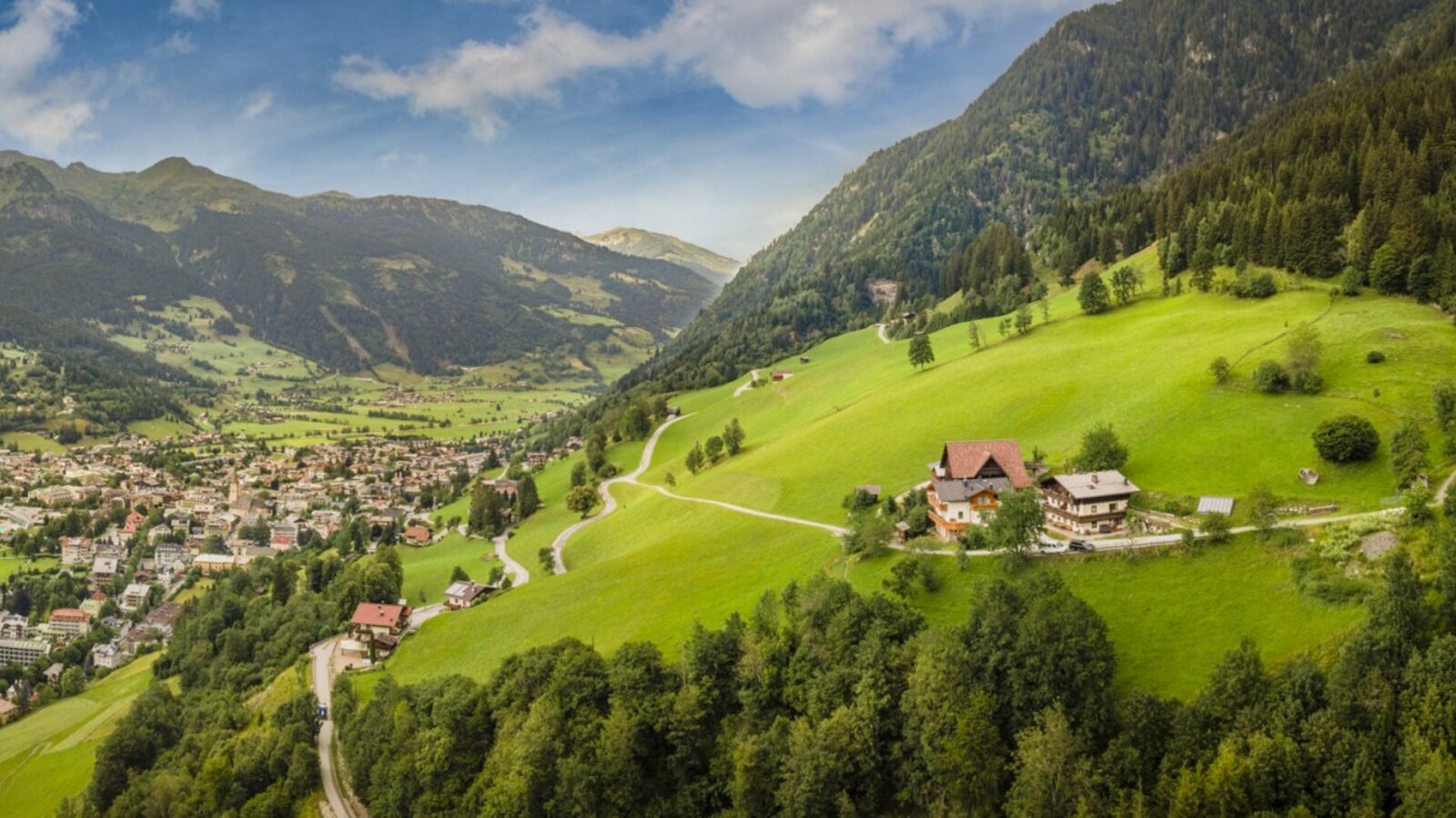 Malerischer Blick auf den Bauernhof, eingebettet in saftig grüne Almwiesen mit einem weiten Panorama über das umliegende Tal.