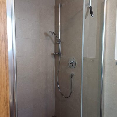 Schlafzimmer mit Doppelbett, zwei Nachttischen, Wandlampen und einer Sitzbank.