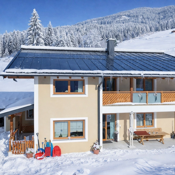 Außenansicht  im Winter mit schneebedeckter Landschaft, einem Balkon im Obergeschoss und einer Terrasse im Erdgeschoss.