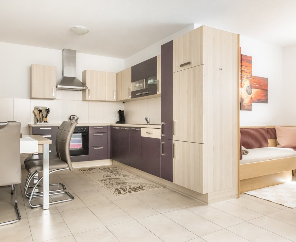 Küche des Bed and Breakfast mit moderner Küchenzeile, Esstisch und angrenzendem Wohnbereich mit Schlafsofa.