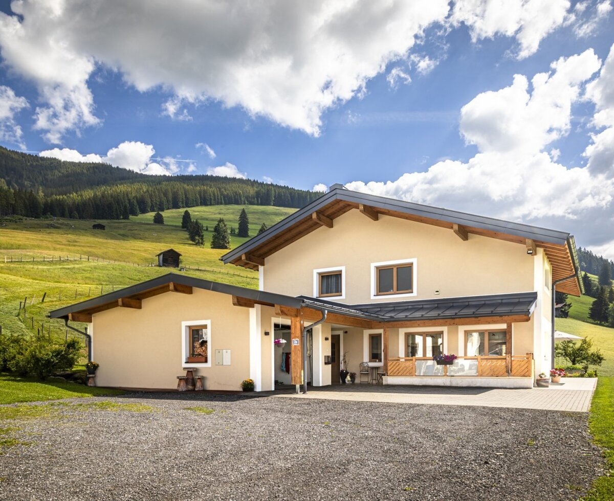 Ein einladendes Bed and Breakfast eingebettet in saftig grüne Berghänge unter strahlend blauem Himmel.