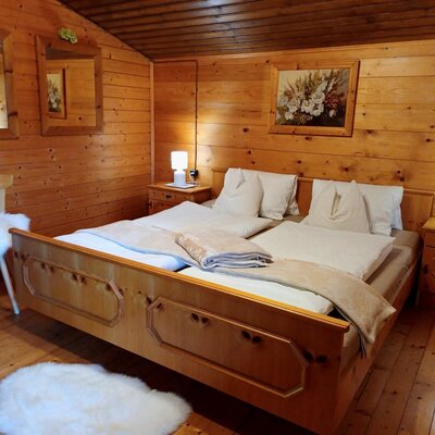 Doppelzimmer im Hof mit Holzvertäfelung, Doppelbett, zwei Nachttischen mit Lampen und einem Stuhl.
