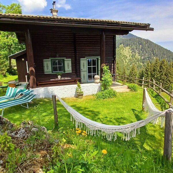Der Hof mit Rasenfläche, Liegestühlen, Hängematte und einer Berglandschaft im Hintergrund.