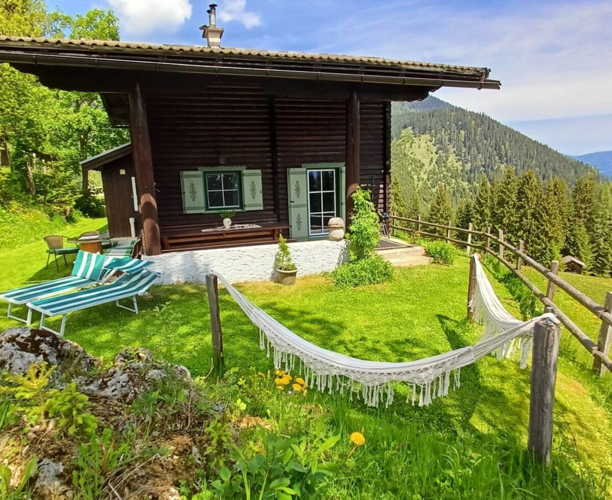Der Hof mit Rasenfläche, Liegestühlen, Hängematte und einer Berglandschaft im Hintergrund.