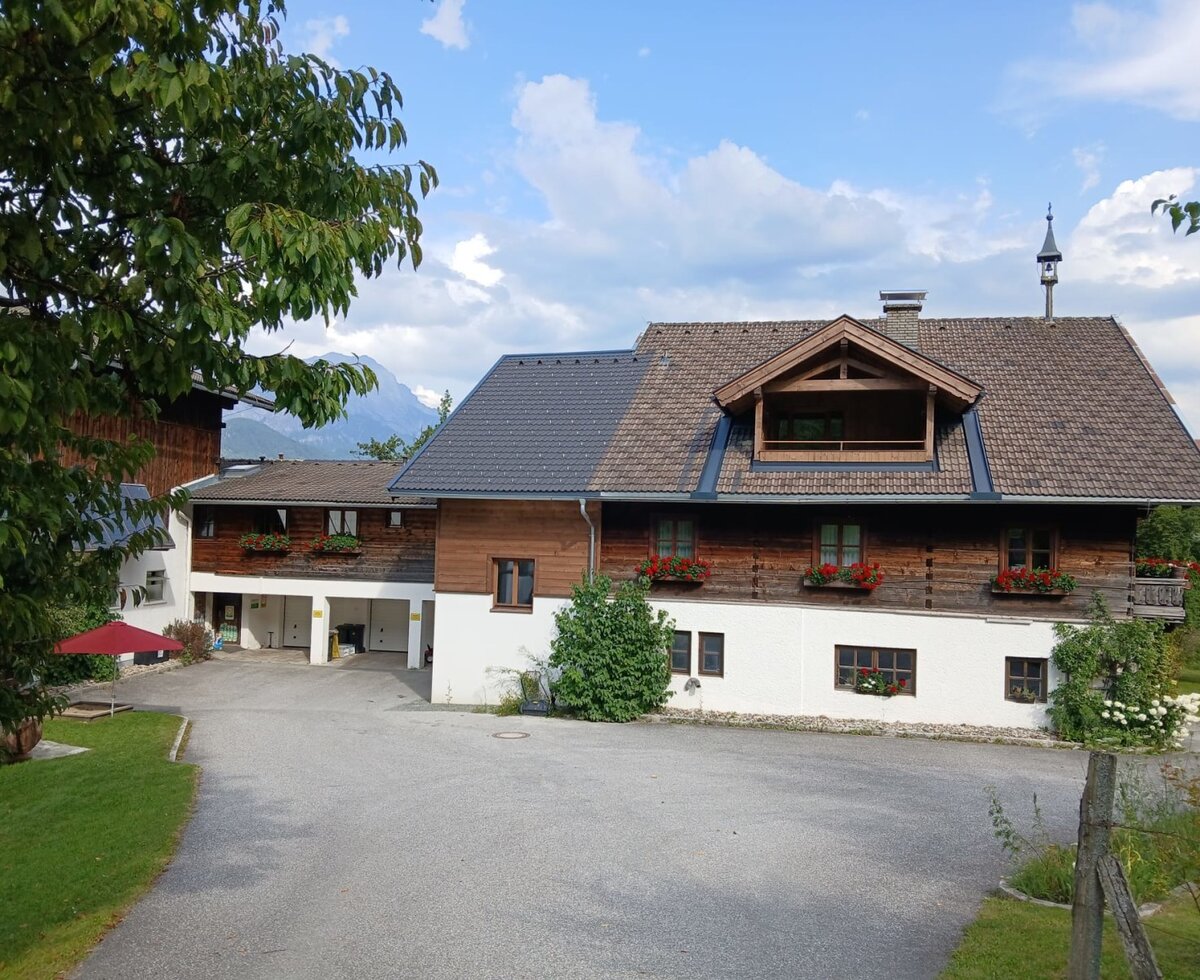 Der einladende Bauernhof Hinterburghof mit seiner traditionellen Holzfassade und blumengeschmückten Fenstern.