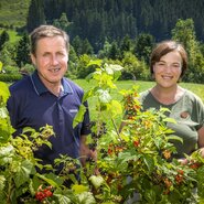 Die Gastgeber des Bauernhofs inmitten ihrer Johannisbeersträucher mit roten und schwarzen Beeren.