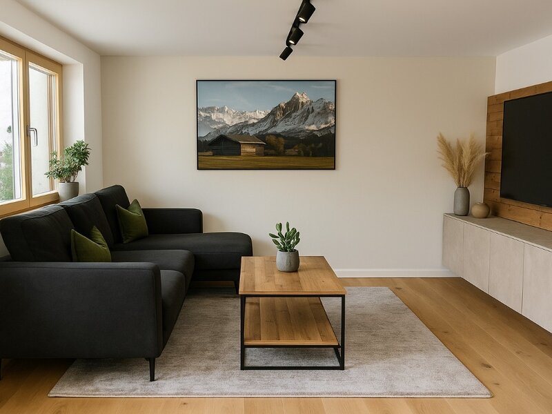 Das Wohnzimmer des Bed and Breakfast bietet ein dunkles L-förmiges Sofa, einen Holztisch und einen Fernseher.