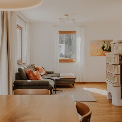 Der helle Wohnbereich des Bauernhofs ist mit einem Ecksofa, einem Kachelofen und Holzboden ausgestattet.