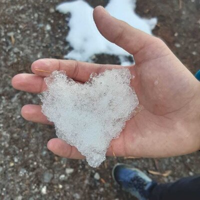 Eine Hand hält Schnee in Herzform.