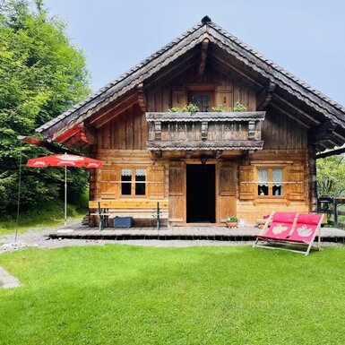 Die Almhütte verfügt über einen Garten mit Rasenfläche, Sonnenliegen, Sitzgelegenheiten im Freien und einem Balkon.