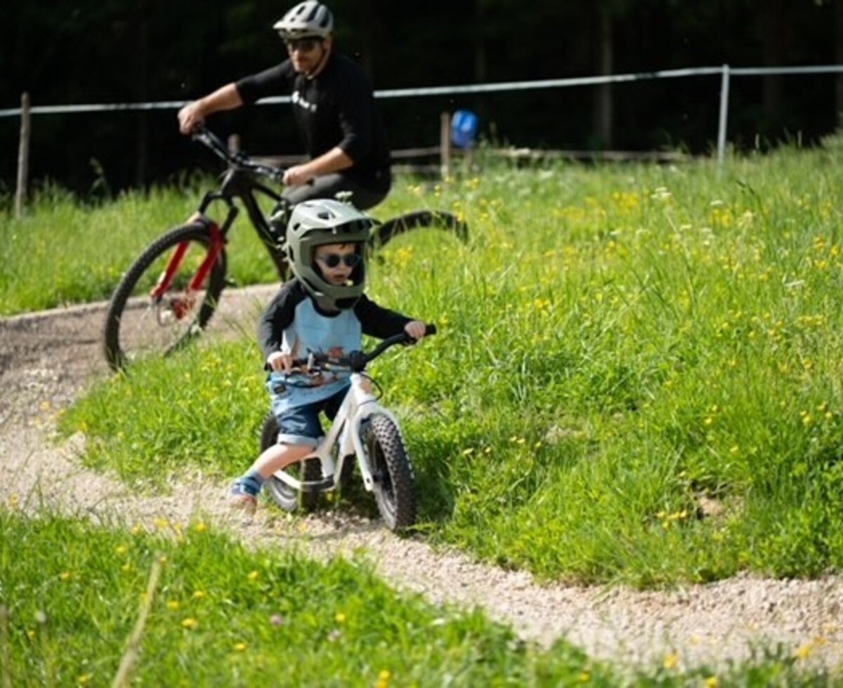 Fahrradfahren für Kinder und Erwachsene auf dem Bauernhof, mit einem Schotterweg und grüner Umgebung.