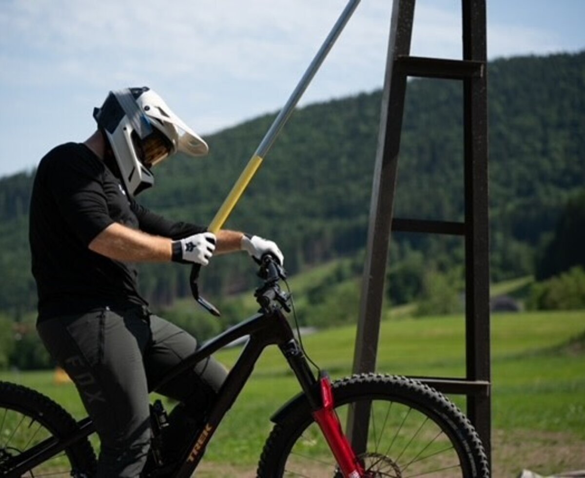 Ein Mountainbiker mit Schutzausrüstung nutzt einen Schlepplift, um die Berge zu erklimmen.