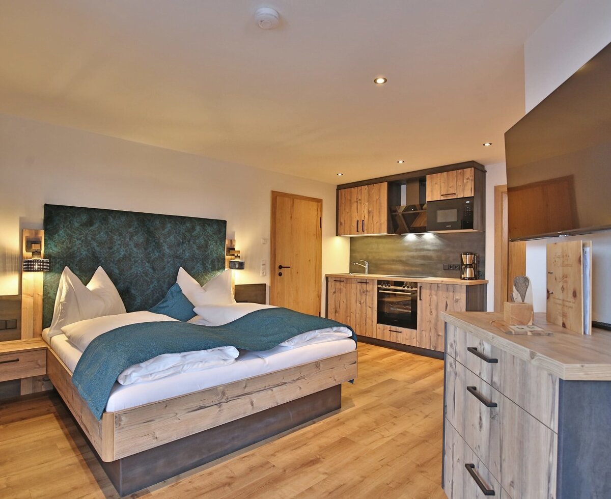 Doppelzimmer auf dem Bauernhof mit Doppelbett, integrierter Küchenzeile und Flachbildfernseher.