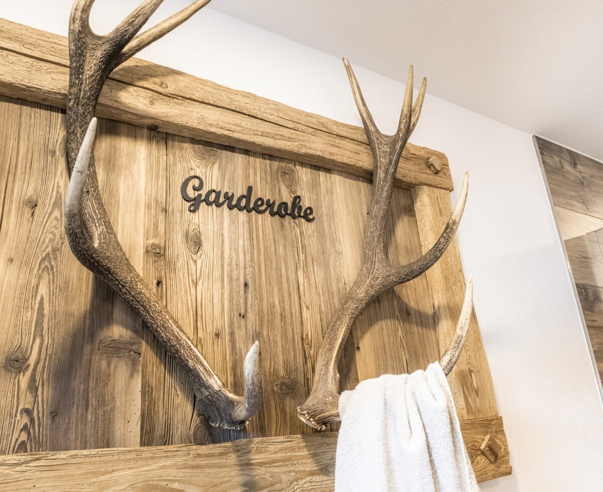 Hölzerne Garderobe mit Geweih und der Aufschrift 'Garderobe'.