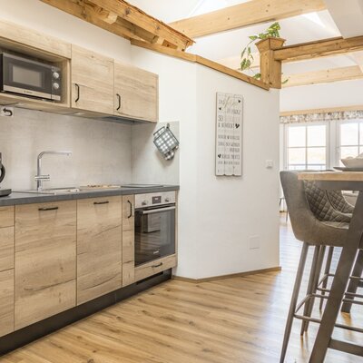 Moderne Küche mit Mikrowelle, Kaffeemaschine, Backofen und einer Frühstückstheke mit Barhockern.