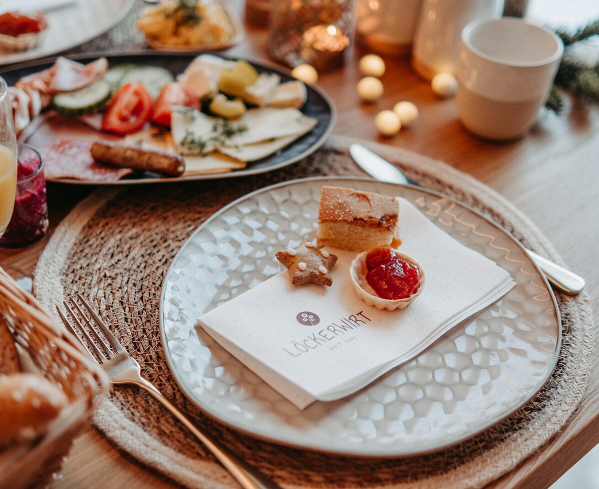 Ein gedeckter Frühstückstisch im Bauernhof mit einer Auswahl an Gebäck, Aufschnitt, Käse und frischem Saft.