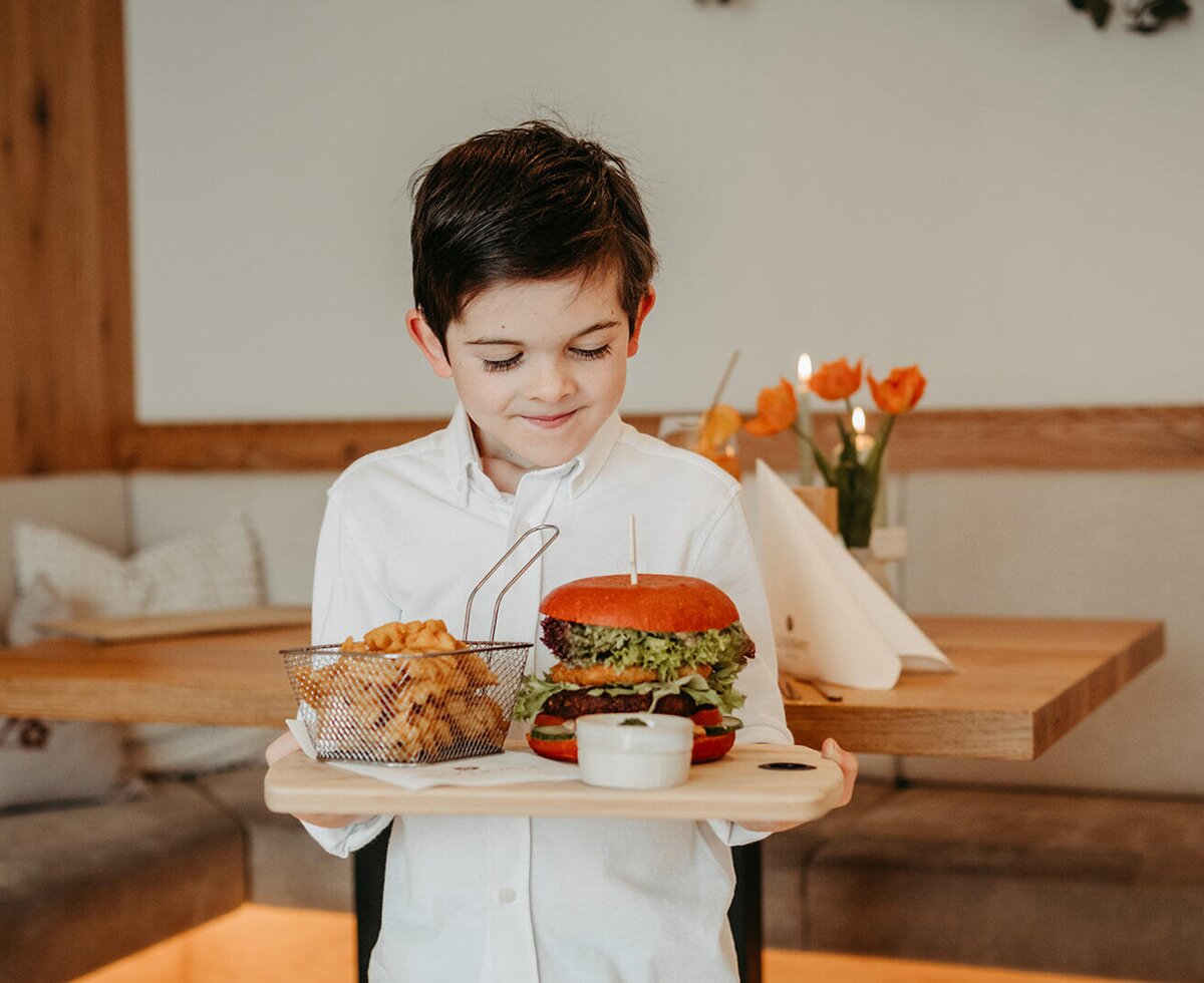 Ein Burger mit Pommes Frites, serviert auf einem Holztablett, im Restaurant des Bauernhofs.