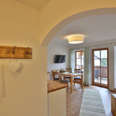 Wohn- und Essbereich mit Esstisch, Fernseher und Zugang zum Balkon.