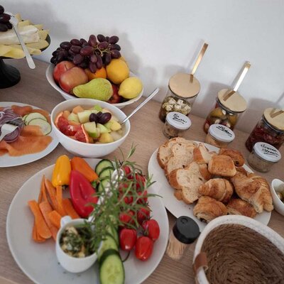 Frühstücksangebot im Bauernhof mit Käse, frischem Obst, Gemüse, Lachs, Brot und Gebäck.