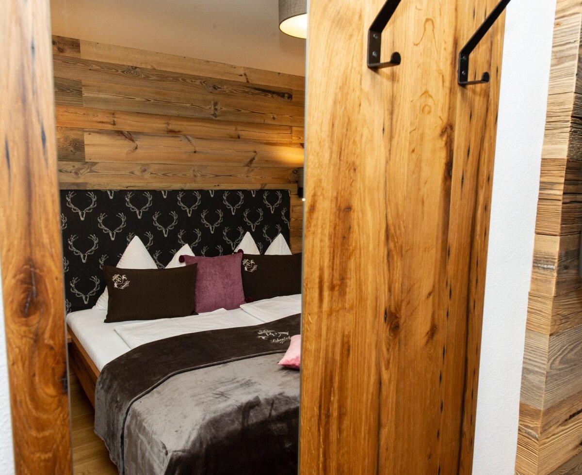 Schlafzimmer im Bauernhof mit Doppelbett, Holzwänden, SAT-TV und Garderobenhaken.
