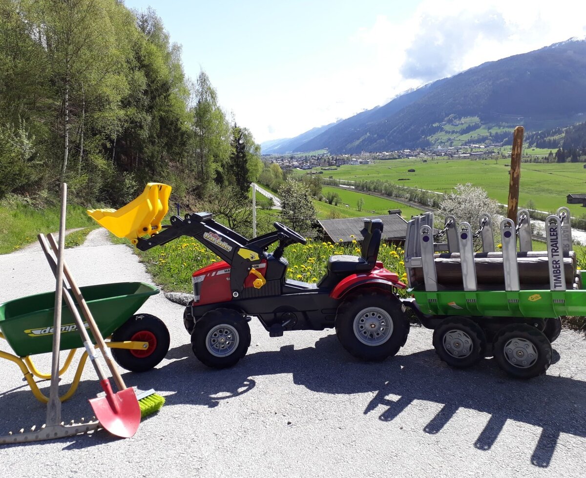Für die kleinen Gäste des Bauernhofs stehen ein Spielzeug-Traktor mit Anhänger, eine Schubkarre und Gartengeräte bereit.