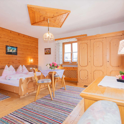 Schlafzimmer im Bed and Breakfast mit Holzdoppelbett, Esstisch, Kleiderschrank und Fenster.