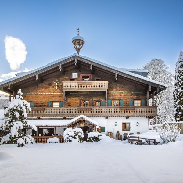 Der Bauernhof im Winter mit Schnee auf dem Dach, den Balkonen und dem umliegenden Grundstück.