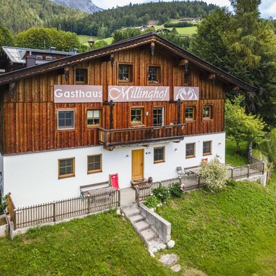 Der einladende Bauernhof Millinghof mit traditioneller Holzfassade, umgeben von grünen Wiesen und Wäldern.