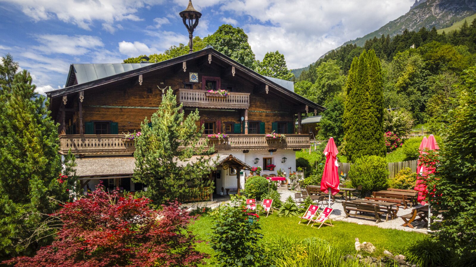 Der einladende Bauernhof mit einem gepflegten Garten, einer gemütlichen Terrasse und schattenspendenden Sonnenschirmen.