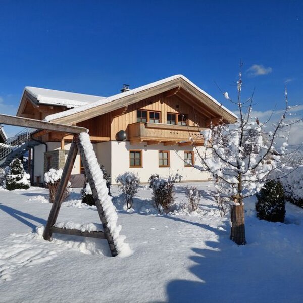 Der Bauernhof im Winterkleid mit Garten, Schaukel und Bergblick.