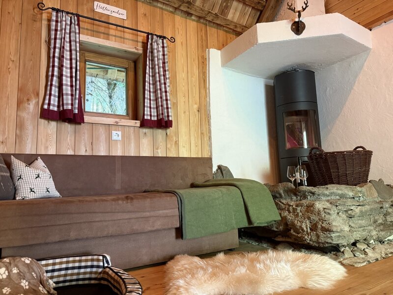 Gemütlicher Wohnbereich des Bed and Breakfasts mit einem einladenden Sofa, rustikalen Holzwänden und einem wärmenden Kaminofen.