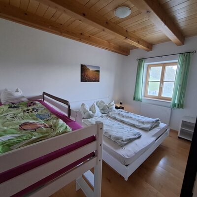Schlafzimmer in der Ferienwohnung mit Doppelbett, Hochbett für Kinder und Blick ins Grüne