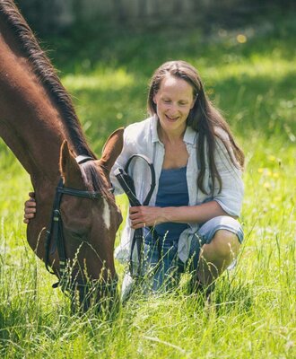 Eine Frau mit einem Pferd auf einer Wiese, was Tierkontakt oder Reitmöglichkeiten für Gäste der Ferienwohnung bietet.