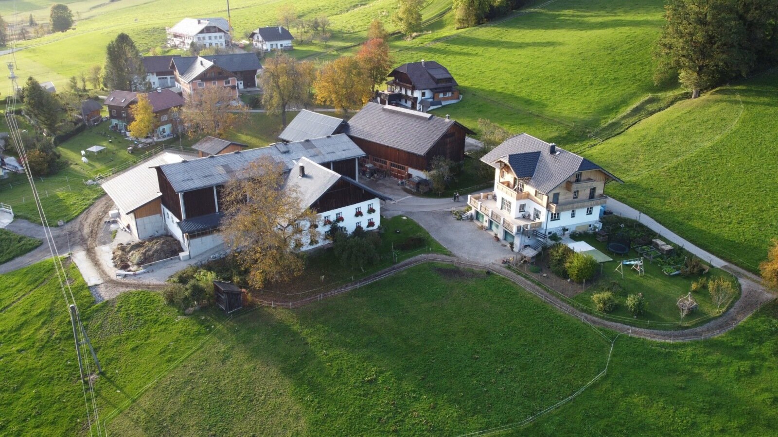 Die Ferienwohnung in ländlicher Umgebung, umgeben von grünen Hügeln, mit einem Garten und Spielgeräten für Kinder.