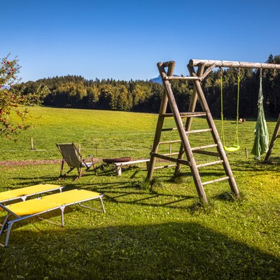 Der weitläufige Garten des Bauernhofs bietet gemütliche Liegestühle, einen Spielplatz aus Holz und einen weiten Blick ins Grüne.