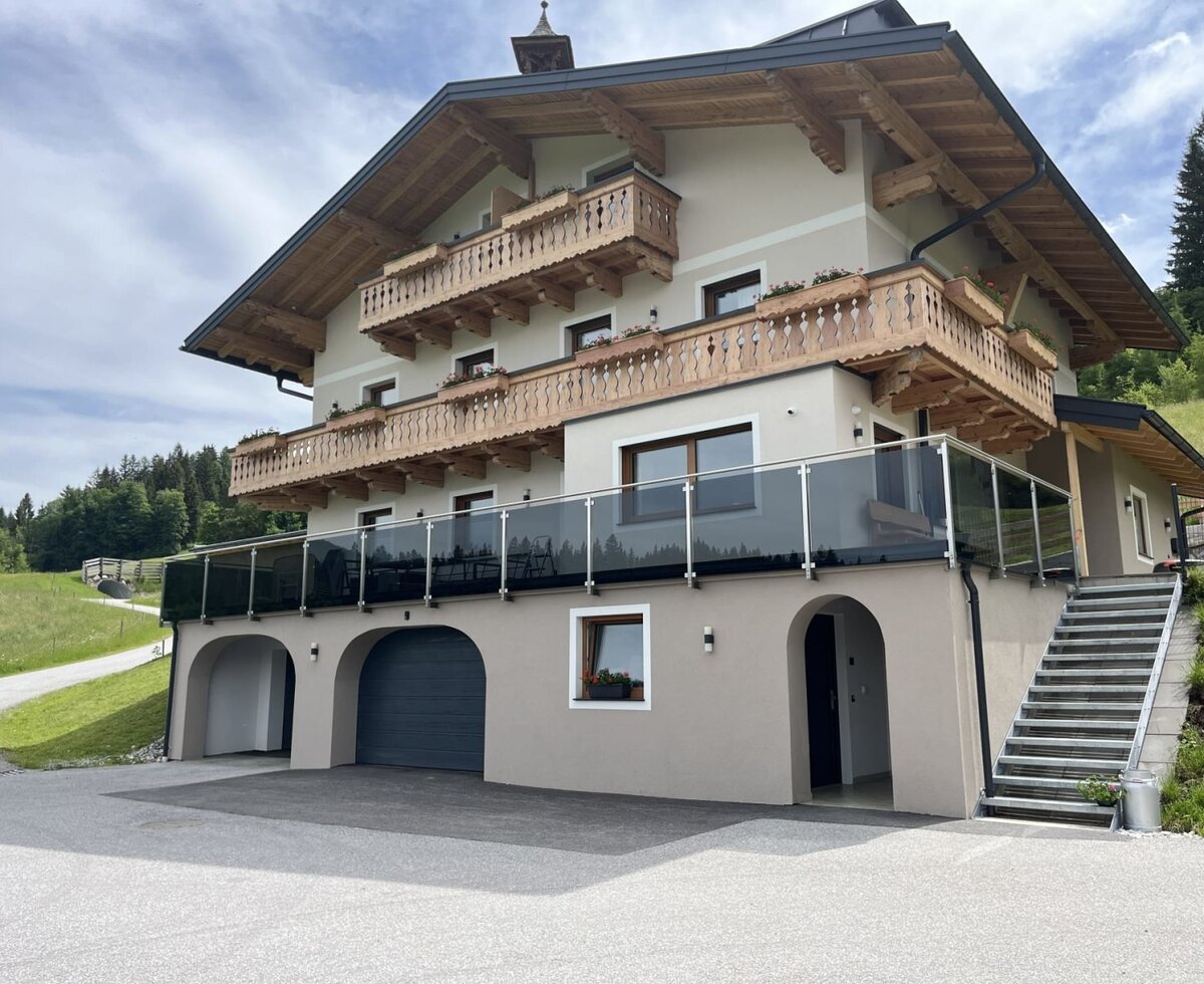 Außenansicht des Bauernhofs mit traditionellen Holzbalkonen und einer modernen Terrasse
