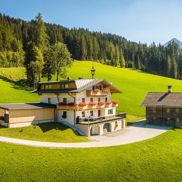 Der einladende Bauernhof Peterlehen in ruhiger, sonniger Hanglage, umgeben von grünen Wiesen und Wäldern.