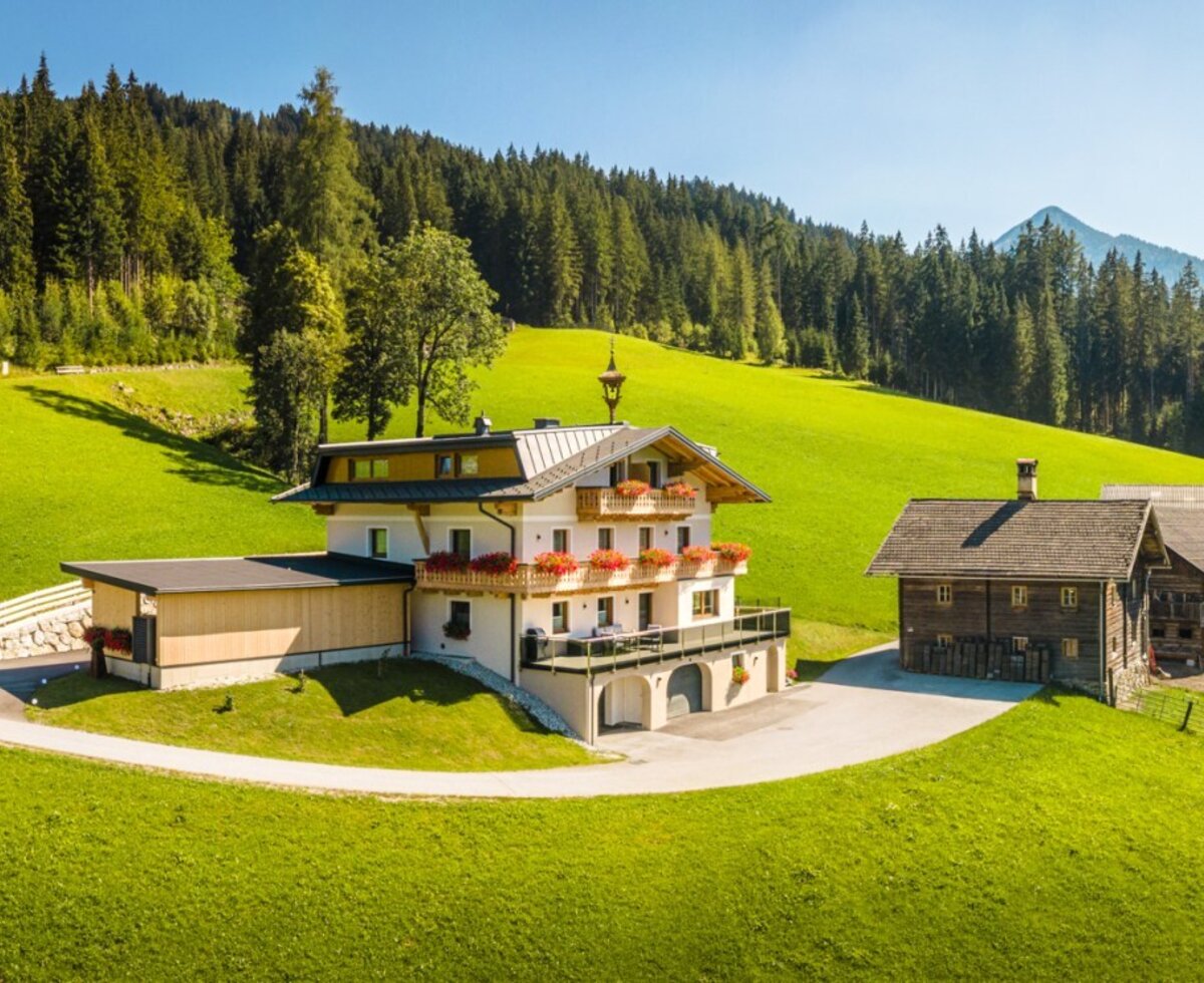 Der einladende Bauernhof Peterlehen in ruhiger, sonniger Hanglage, umgeben von grünen Wiesen und Wäldern.