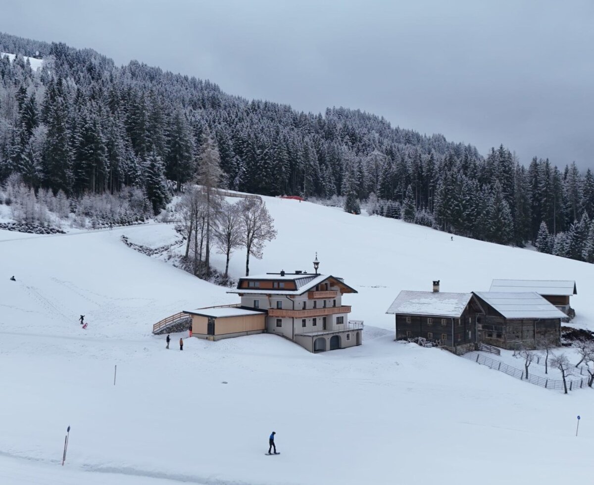 Der idyllische Bauernhof inmitten einer verschneiten Winterlandschaft, direkt an der Piste und umgeben von verschneiten Wäldern.