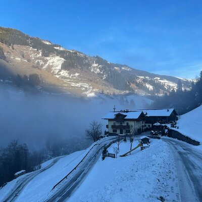 Der Bauernhof in einer verschneiten Berglandschaft mit Nebel im Tal.