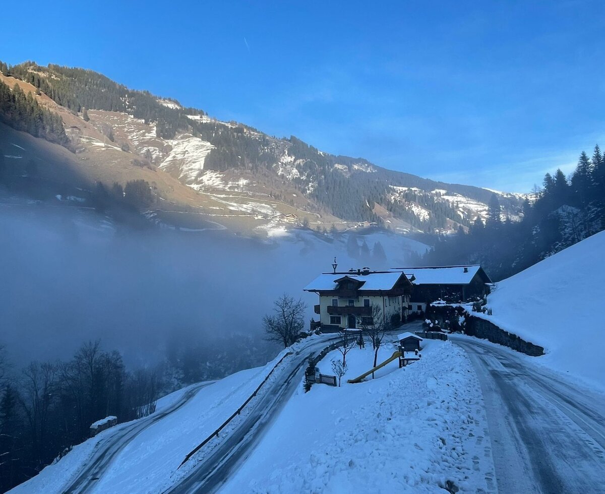 Der Bauernhof in einer verschneiten Berglandschaft mit Nebel im Tal.