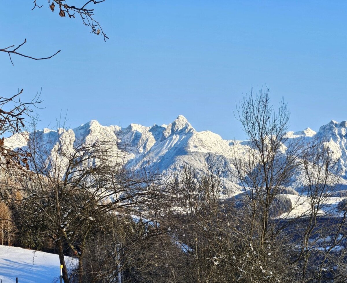 Blick vom Bauernhof auf die schneebedeckten Berge des Tennengebirges.