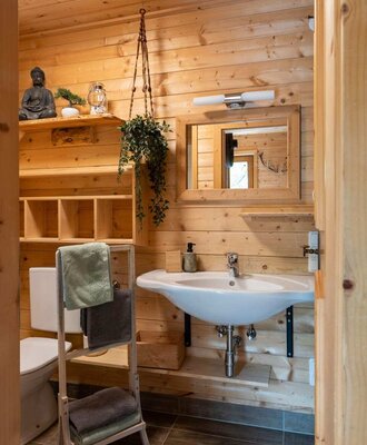 Ein gemütliches Badezimmer der Alm mit hellen Holzwänden, einem Waschbecken und einem praktischen Handtuchhalter.